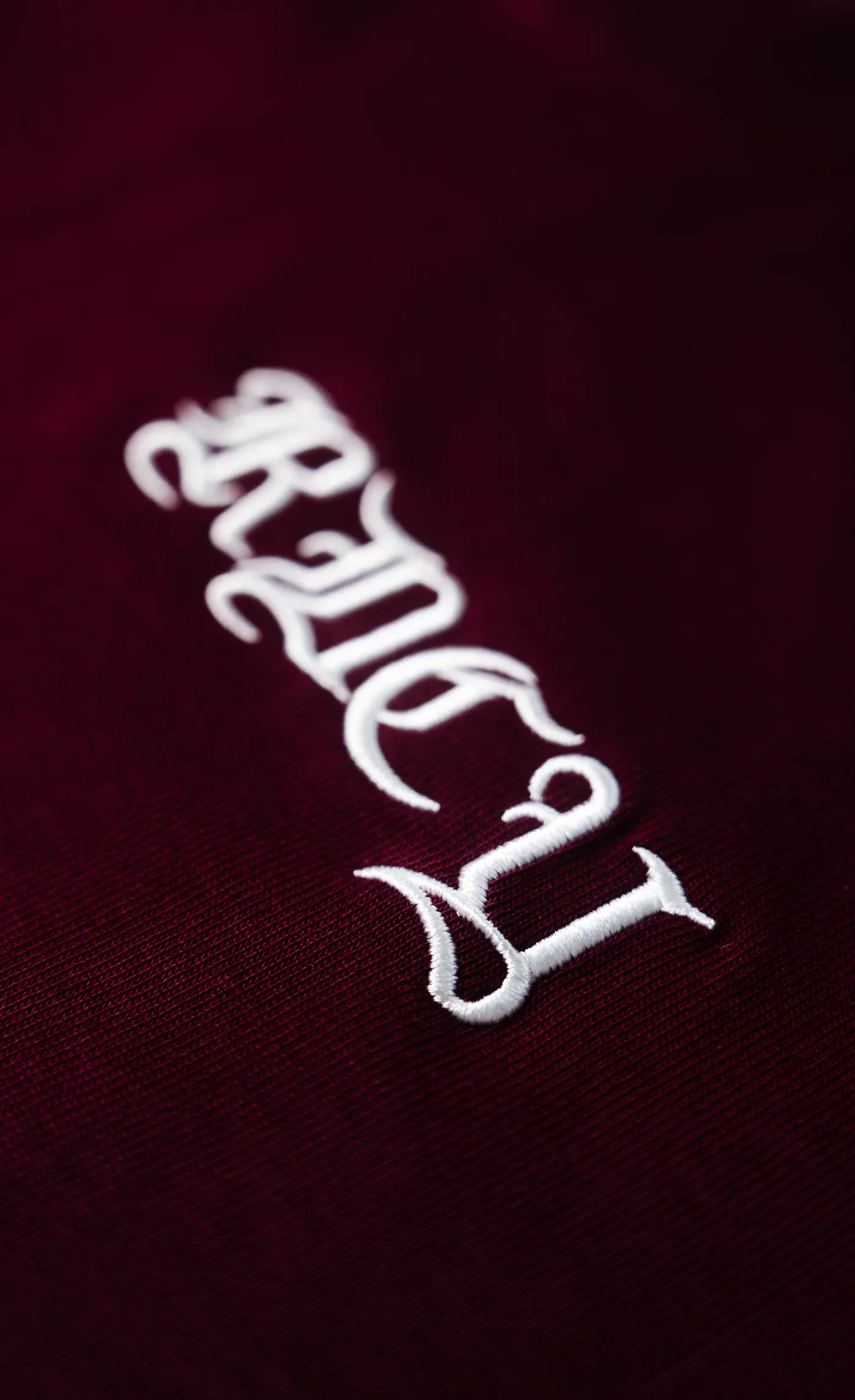 Raised white blackletter embroidery on burgundy velvet